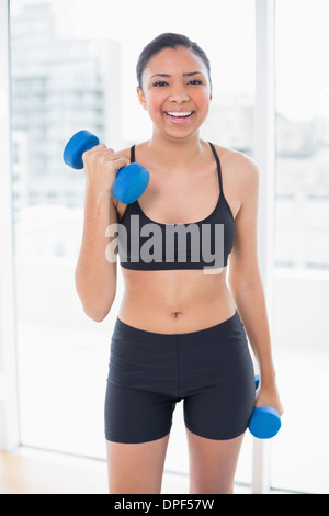 Ridendo dai capelli scuri modello in sportswear esercizio con manubri Foto Stock