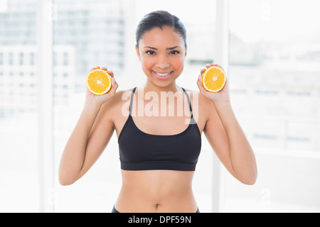 Bella dai capelli scuri modello in azienda di abbigliamento sportivo di metà arancione Foto Stock