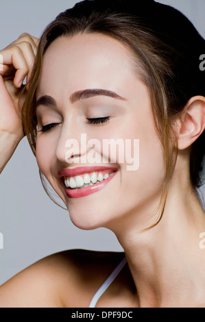 Studio Ritratto di giovane donna sorridente con gli occhi chiusi Foto Stock