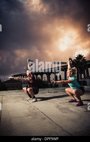 Uomo e donna kettlebells sollevamento palestra sul tetto Foto Stock