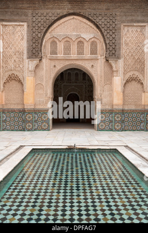 Cortile e piscina con tradizionale marocchino portale ornato in Ben Youssef Medersa, sito UNESCO, Marrakech, Marocco Foto Stock