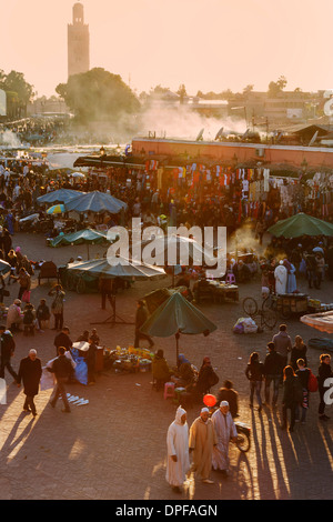 La vivace piazza di Piazza Jemaa el Fna con il minareto della Moschea Koutoubia in distanza, sito UNESCO, Marrakech, Marocco Foto Stock