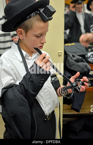 I giovani religiosi ragazzo ebreo mette su phylacteries - teffilin - presso la sinagoga Lubavitch in Crown Heights, Brooklyn, New York Foto Stock