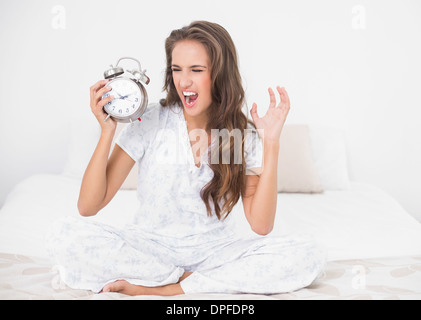 Furious brunette holding sveglia Foto Stock