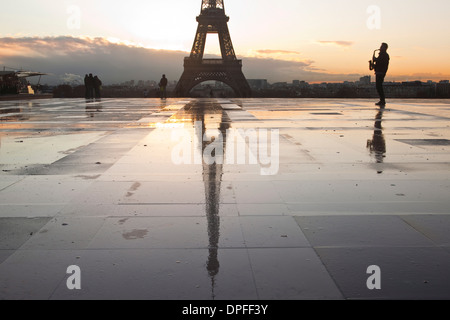 Un uomo giocando un sassofono davanti alla Torre Eiffel, Parigi, Francia, Europa Foto Stock