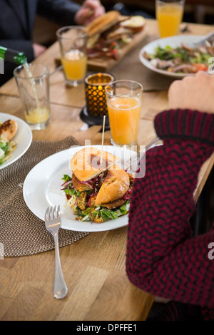 Giovane donna con il Burger nella piastra Foto Stock