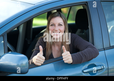 Un driver di successo guardando fuori della finestra e mostra pollice in alto Foto Stock