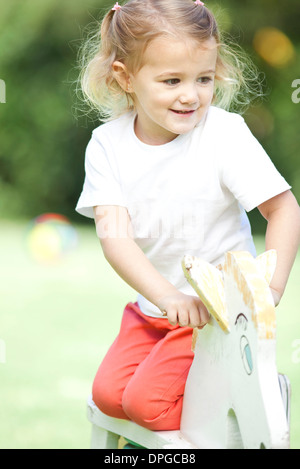 Bambina knneling sul cavallo a dondolo, ritratto Foto Stock