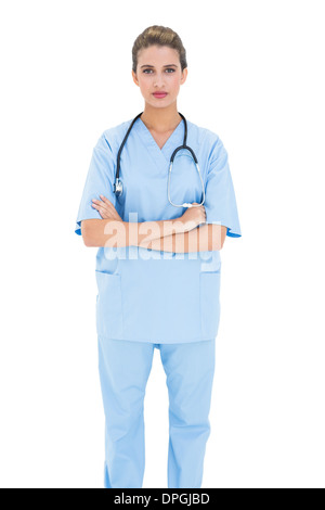Gravi dai capelli marroni infermiere in blu scrubs in posa con le braccia incrociate Foto Stock