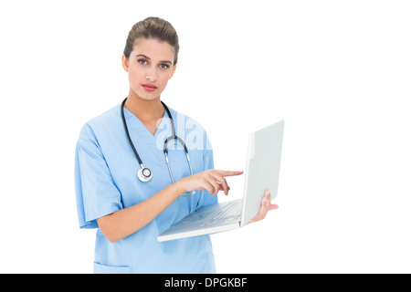 Stern brown pelose infermiere in blu frega usando un computer portatile Foto Stock