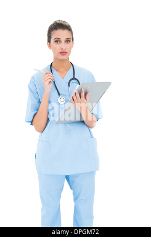 Gravi dai capelli marroni infermiere in blu frega la verifica di una relazione Foto Stock