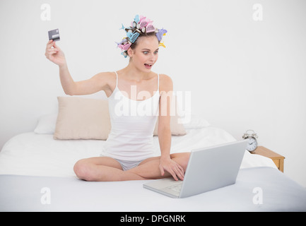 Stupiti marrone naturale donna dai capelli in arricciacapelli shopping online con un computer Foto Stock