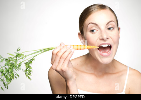 Giovane donna di mangiare la carota Foto Stock