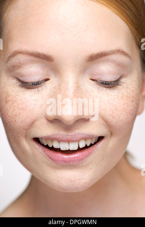 Giovane donna che guarda verso il basso, sorridente, close-up verticale Foto Stock