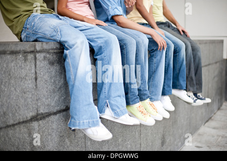 Amici seduti insieme sulla parete bassa, sezione bassa Foto Stock