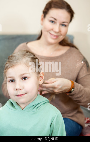 Madre saccheggiare i capelli del suo bambino seduto in ambiente domestico Foto Stock