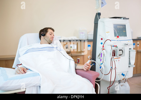 Paziente ascolto la musica mentre riceve la dialisi renale Foto Stock