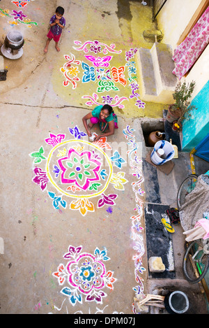 Ragazza indiana rendendo Rangoli festival di polvere colorata progetta a Sankranti in un territorio rurale villaggio indiano. Andhra Pradesh, India Foto Stock