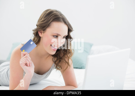 Donna informale facendo shopping online a letto Foto Stock