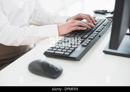 La sezione centrale di imprenditrice utilizzando la tastiera del computer in ufficio Foto Stock