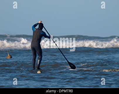 Stand Up Paddle boarder dirigendosi verso le onde, Bude, Cornwall, Regno Unito Foto Stock