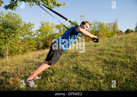 Un uomo utilizza gli anelli di sospensione Foto Stock