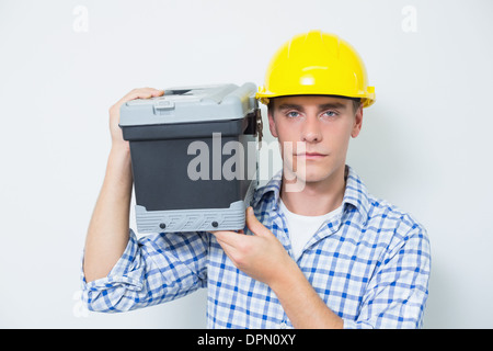 Grave tuttofare nel casco giallo trasportano toolbox Foto Stock