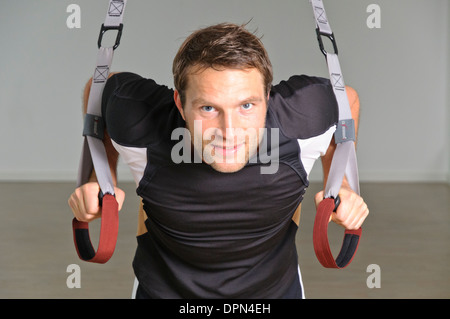 Un uomo utilizza gli anelli di sospensione Foto Stock