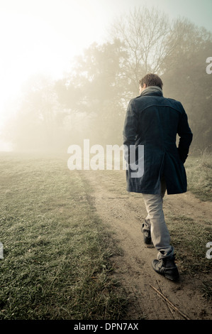 Uomo passa attraverso la nebbia di mattina Foto Stock