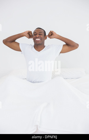 Afro uomo svegliarsi nel letto e stirando le braccia Foto Stock