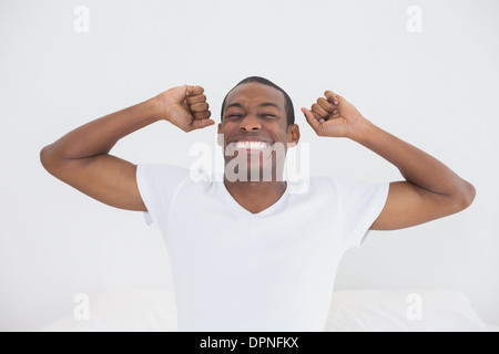 Afro uomo svegliarsi nel letto e stirando le braccia Foto Stock