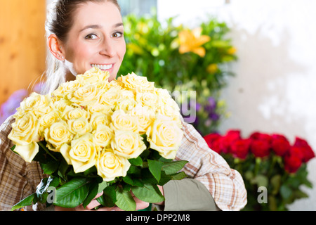 Fiorista femmina nel negozio di fiori o vivaio presentando le rose Foto Stock