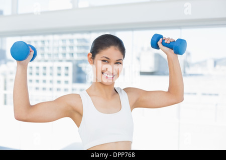 Montare donna esercizio con manubri in studio fitness Foto Stock