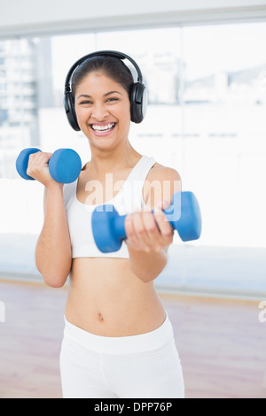 Donna allegra esercizio con manubri in studio fitness Foto Stock