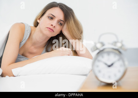 Stanco giovane donna che giace sotto il coperchio sul suo letto Foto Stock