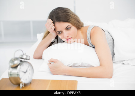 Calma e attraente donna sdraiata riflessivo sul suo letto Foto Stock