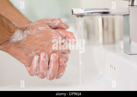 Lavarsi le mani con sapone in acqua corrente Foto Stock