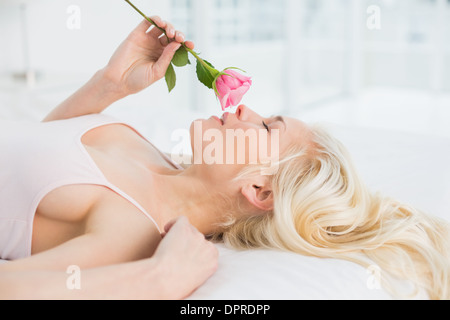 Vista laterale di una bella donna nel letto con rose Foto Stock