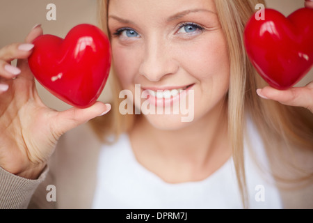 Immagine della donna sorridente con due cuori rossi in mani guardando la fotocamera Foto Stock
