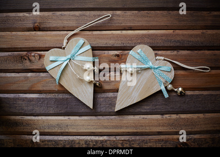 Immagine dei cuori di legno con nastri blu e perle su sfondo di legno Foto Stock