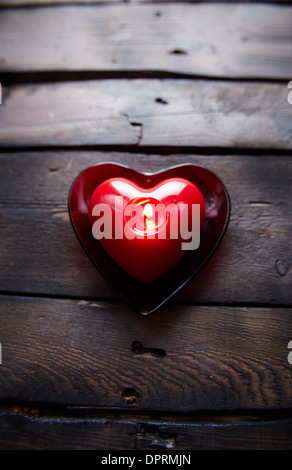 Immagine di colore rosso a forma di cuore la masterizzazione di candela su sfondo di legno Foto Stock