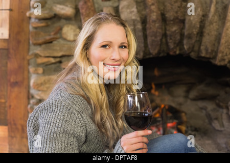 Bella donna con wineglass davanti al caminetto acceso Foto Stock