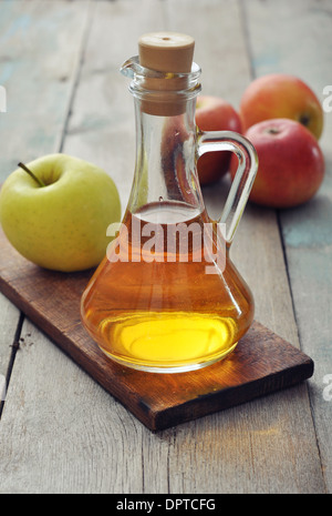 Apple di aceto di sidro in una bottiglia di vetro e mele fresche Foto Stock