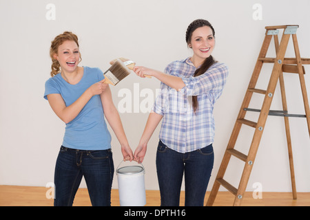 Amici holding pennelli e può in una nuova casa Foto Stock