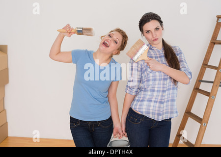 Amici holding pennelli e può in una nuova casa Foto Stock