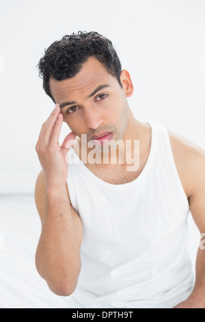 Giovane uomo che soffre di mal di testa nel letto Foto Stock