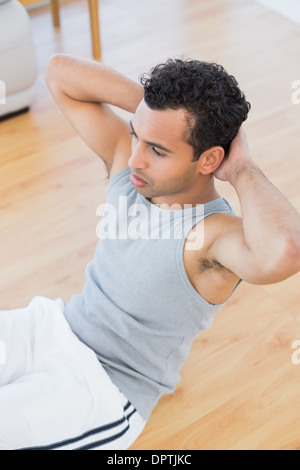 Giovane uomo facendo sgranocchia addominale nel soggiorno Foto Stock