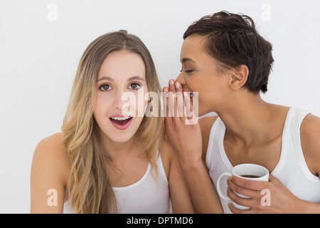 Giovani amici di sesso femminile con tazza di caffè spettegolare Foto Stock