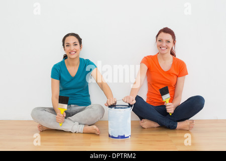 Amici con pennelli e vernice possono sedersi in una nuova casa Foto Stock