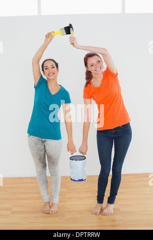 Sorridendo gli amici con i pennelli e la vernice può nella nuova casa Foto Stock